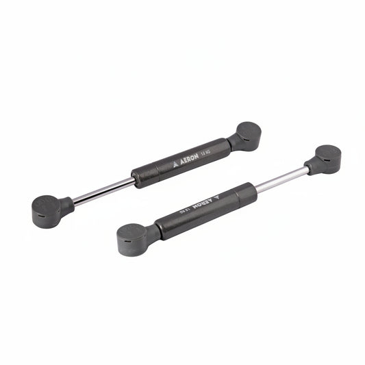 A pair of Aeron 6-inch hydraulic gas pumps in a durable charcoal grey finish, each featuring a 15kg load-bearing capacity. These compact pneumatic lift supports are equipped with reinforced ball joint connectors, specifically designed to provide high-pressure lift and smooth, controlled movement for heavy cabinet doors, specialized storage hatches, and compact furniture lid applications.