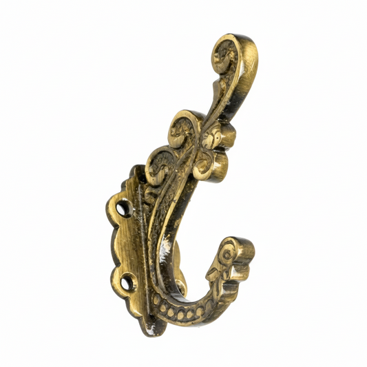 An ornate Victorian-style wall hook featuring intricate scrollwork and floral patterns in an antique brass finish, designed with two mounting holes on a decorative backplate for use as a high-end coat, hat, or accessory holder.