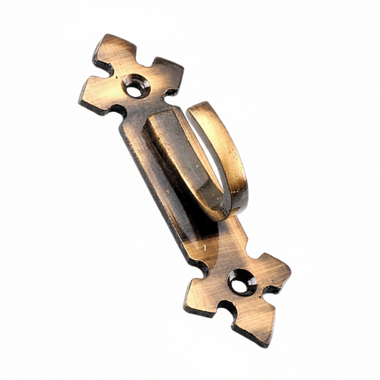 A single decorative wall hook crafted from solid metal with an antique brass finish, featuring a stylized fleur-de-lis backplate with two pre-drilled mounting holes and a sturdy curved hook for hanging keys, hats, or curtain tiebacks.