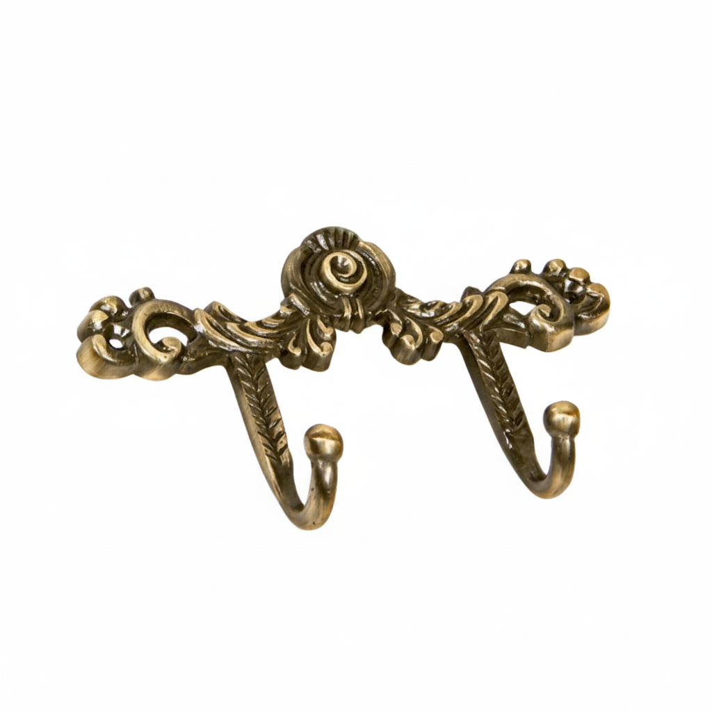 An ornate Victorian-style double wall hook featuring intricate scrollwork, a central rose motif, and acanthus leaf details in an antique brass finish. The decorative metal hardware includes two curved hooks with ball tips, perfect for hanging coats or accessories in a luxury interior.