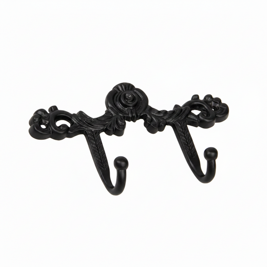 An ornate Victorian-style double wall hook featuring intricate scrollwork, a central floral rose motif, and acanthus leaf details in a sleek black finish. The decorative metal hardware includes two curved hooks with smooth ball tips, designed for hanging coats or accessories in a modern or classic interior.