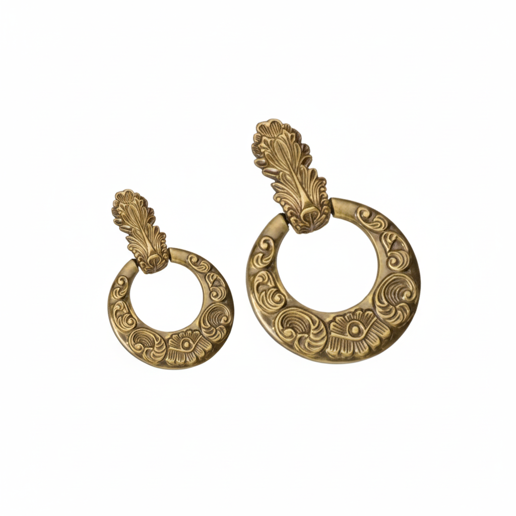 A pair of ornate drop ring handles in two sizes, crafted with an antique brass finish and featuring intricate acanthus leaf mounting brackets and etched scrollwork patterns on the circular rings for traditional furniture and cabinet decoration.