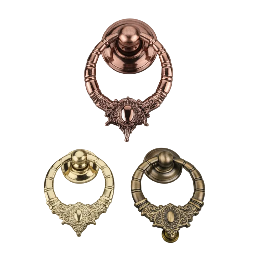 A collection of three ornate circular ring pull handles for furniture and cabinets, featuring detailed filigree scrollwork at the base and ribbed textures. The set is displayed in three premium metallic finishes Antique Brass, rose gold,  and gold.