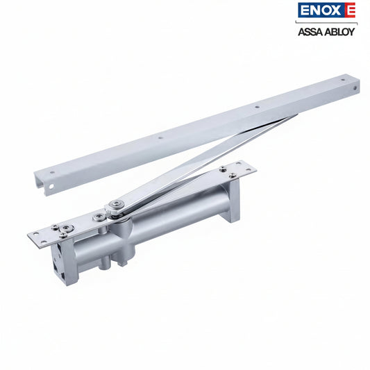 An ENOX (Assa Abloy) concealed overhead hydraulic door closer with a premium satin silver finish. The unit features a high-precision guide rail and sliding arm assembly designed for "invisible" installation within the door leaf or frame. This architectural-grade hardware provides smooth, adjustable hydraulic control, ideal for minimalist modern interiors in luxury residential and commercial office spaces.