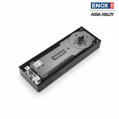 A high-performance ENOX (Assa Abloy) hydraulic floor spring closer body housed in a durable black cement box. This architectural hardware features a robust cast iron mechanism with integrated adjustment valves for closing and latching speeds. Designed for recessed floor mounting, it provides invisible, heavy-duty door control for frameless glass, timber, or metal doors in high-traffic commercial and luxury residential entrances.