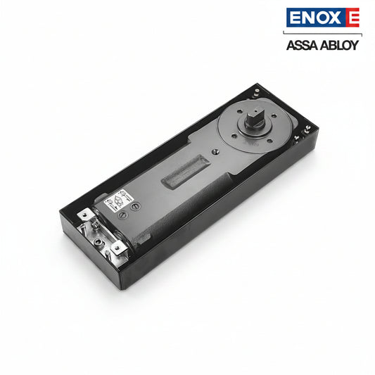 A high-performance ENOX (Assa Abloy) hydraulic floor spring closer body housed in a durable black cement box. This architectural hardware features a robust cast iron mechanism with integrated adjustment valves for closing and latching speeds. Designed for recessed floor mounting, it provides invisible, heavy-duty door control for frameless glass, timber, or metal doors in high-traffic commercial and luxury residential entrances.