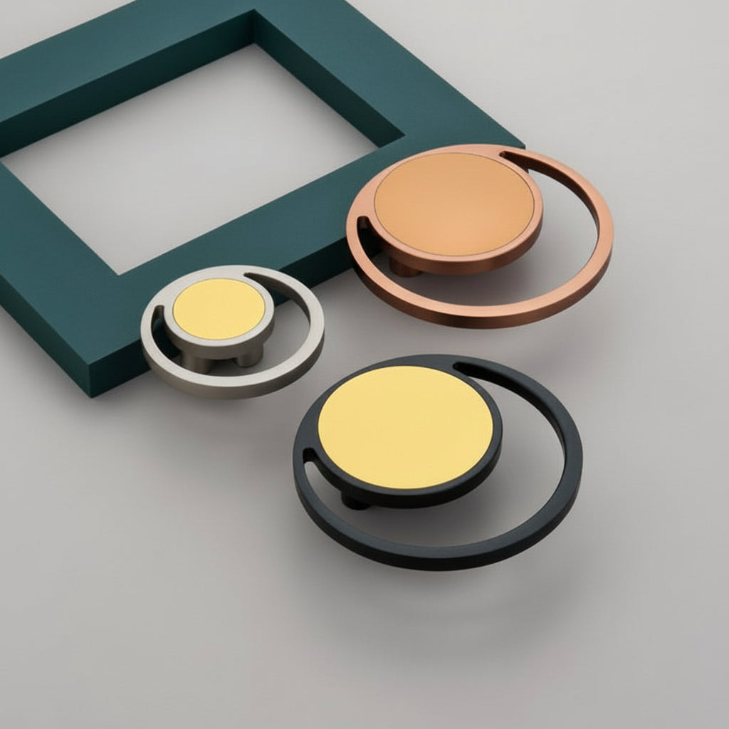A collection of Creatick DH-101 conceptual circular cabinet knobs featuring a unique "ring-within-a-ring" geometric design. These modern artistic pulls are shown in matte black with gold, brushed rose gold, and satin silver finishes, displayed against a minimalist grey and teal background—perfect for avant-garde kitchen cabinetry and designer furniture hardware.