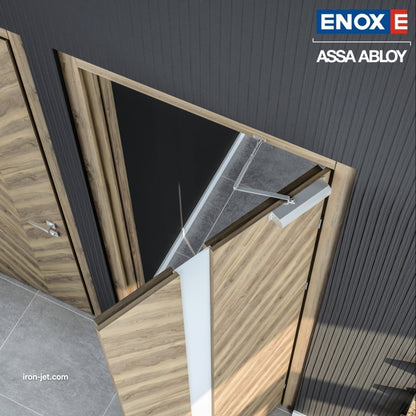 An installed ENOX (Assa Abloy) concealed overhead door closer on a modern light-wood grain interior door. The image showcases the hidden hydraulic mechanism and its sliding arm integrated into the door frame, maintaining a clean architectural aesthetic. This professional installation in a high-end office or residential setting demonstrates how concealed hardware provides smooth, controlled door closing without visible surface-mounted units.