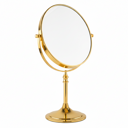 Grafiqe freestanding circular pedestal mirror in a brilliant gold finish, featuring a 360-degree double-sided swivel head for standard and magnified views on a sleek stem and a sturdy weighted base.