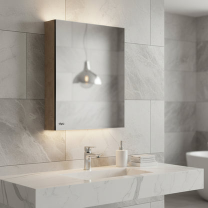 Lifestyle shot of a Grafiqe wall-mounted bathroom mirror cabinet with integrated ambient backlighting, installed above a white marble vanity sink in a modern gray marble-tiled bathroom.