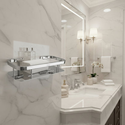 Lifestyle view of a Grafiqe silver stainless steel rectangular shelf holding towels and toiletries, installed on a white marble wall next to a luxury vanity with a backlit mirror, chrome faucets, and warm ambient lighting.