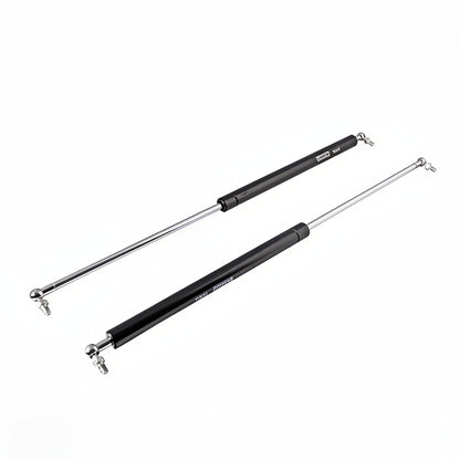 A pair of heavy-duty black gas struts with polished silver hydraulic rods and ball joint connectors. These premium lift supports are designed for smooth, controlled opening and closing of cabinet doors, storage lids, and automotive hoods, featuring a high-pressure pneumatic mechanism for reliable soft-close performance and long-lasting durability.