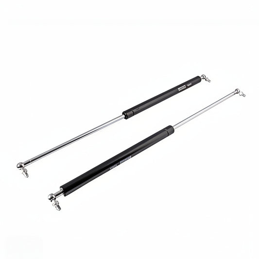 A pair of heavy-duty black gas struts with polished silver hydraulic rods and ball joint connectors. These premium lift supports are designed for smooth, controlled opening and closing of cabinet doors, storage lids, and automotive hoods, featuring a high-pressure pneumatic mechanism for reliable soft-close performance and long-lasting durability.