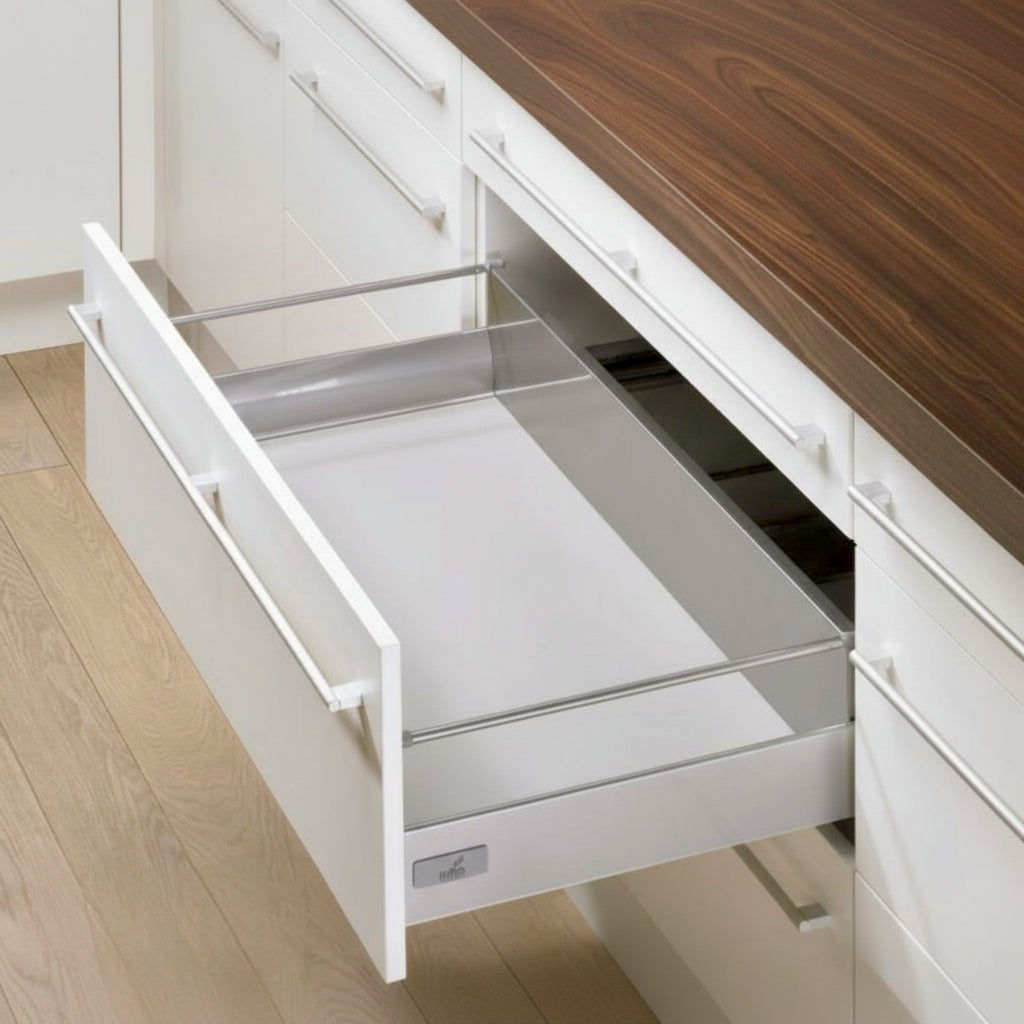 An open high-capacity Hettich double-wall kitchen drawer featuring integrated gallery stability rails and a premium silver finish. The drawer is installed in a modern white cabinet under a natural wood countertop, showcasing German-engineered hardware designed for secure storage of tall kitchenware.
