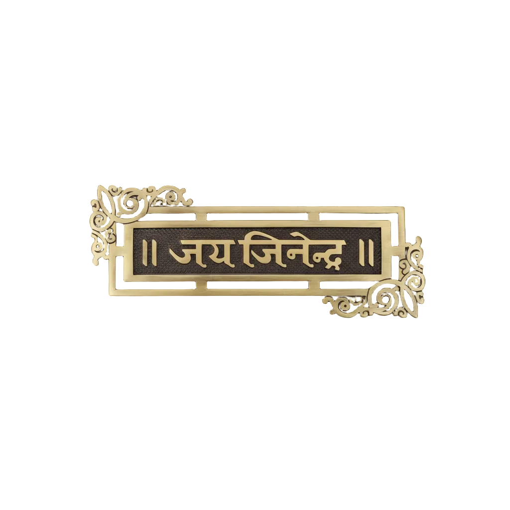 A horizontal Jai Jinendra wall-mounted name plate crafted in antique brass with a black textured background, featuring ornate floral scrollwork on the corners, designed for Jain home temple or entrance decoration.