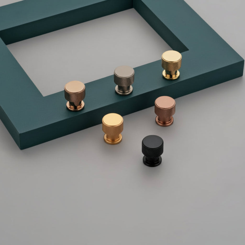 A collection of Creatick KB-05 modern knurled cabinet knobs featuring a textured diamond pattern for enhanced grip. These premium cylindrical furniture knobs are shown in matte black, satin gold, rose gold, and brushed gray finishes, displayed on a minimalist gray and teal surface—perfect for industrial-style kitchen cabinets and luxury drawer hardware.