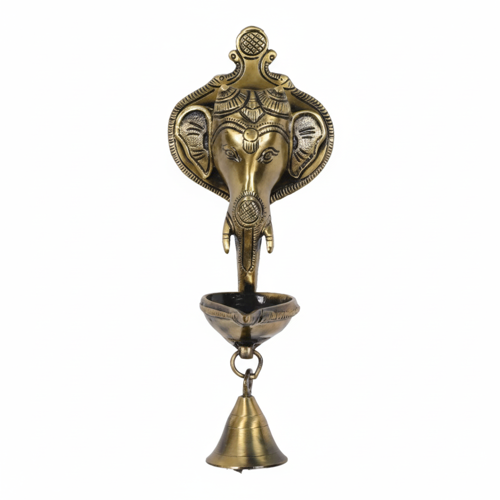 An antique brass wall-mounted hanging oil lamp (diya) featuring a Lord Ganesha head backplate with a single oil wick bowl and a hanging puja bell, designed for home temple or pooja room decoration.