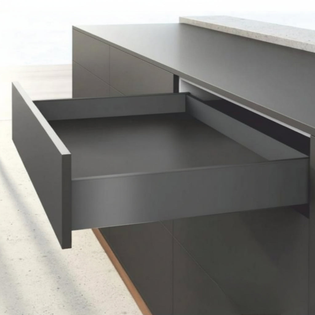 An open minimalist kitchen drawer featuring a premium matte anthracite finish and ultra-slim double-wall sides. The drawer is integrated into dark handle-less cabinetry under a grey countertop, showcasing high-performance hardware designed for seamless modern interior organization.