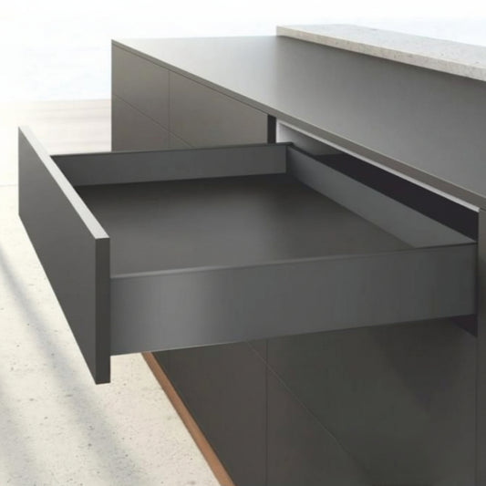 An open minimalist kitchen drawer featuring a premium matte anthracite finish and ultra-slim double-wall sides. The drawer is integrated into dark handle-less cabinetry under a grey countertop, showcasing high-performance hardware designed for seamless modern interior organization.