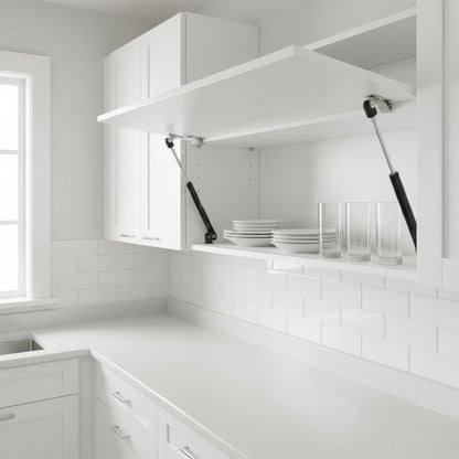 A bright, modern white kitchen featuring an overhead cabinet held open by two black 9-inch hydraulic gas pumps. The image showcases the lift supports providing hands-free access to organized dishes and glassware, highlighting the smooth functionality and space-saving design of pneumatic struts in contemporary kitchen cabinetry.