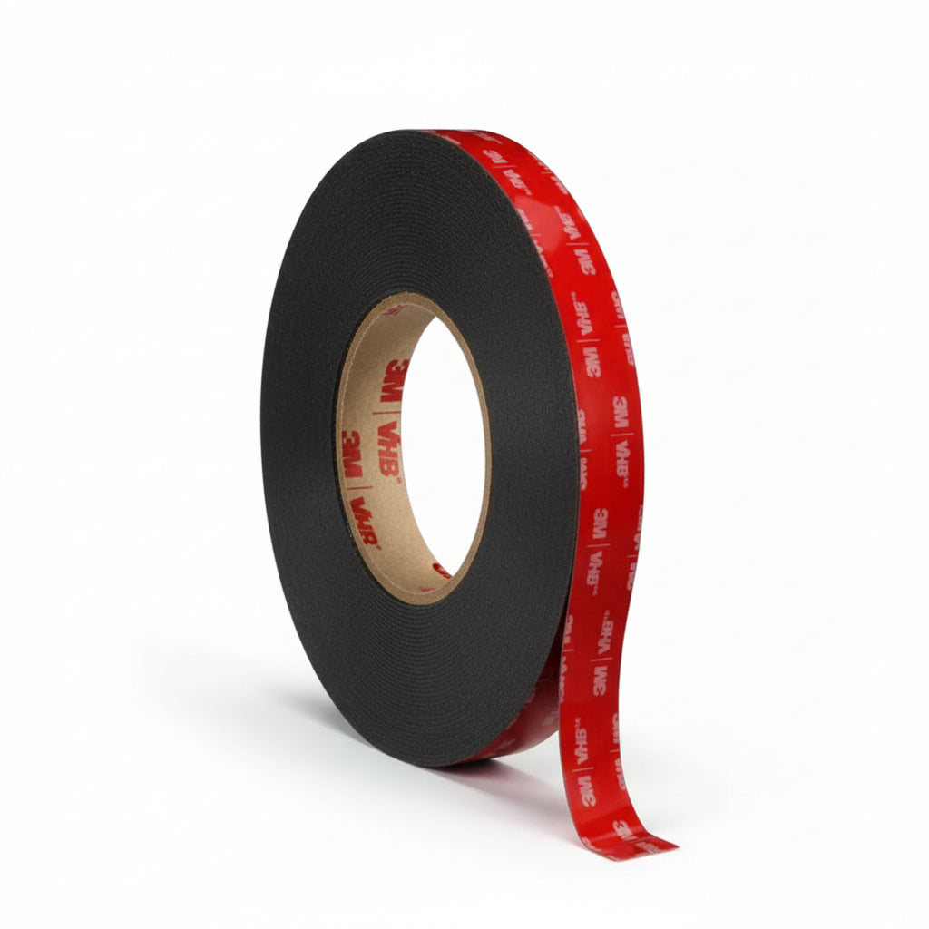 A roll of 3M VHB double-sided black foam tape with a red branded liner. This 12mm x 5m heavy-duty adhesive mounting tape is ideal for industrial-strength bonding on automotive, home, and office surfaces.